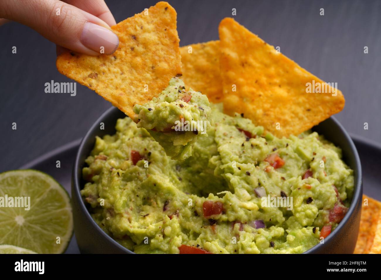 Guacamole et chips ou nachos en plaque noire sur fond noir Banque D'Images