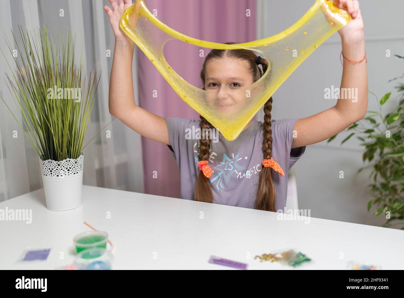 une fille joue avec un élastique jaune et s'amuse à la maison Banque D'Images