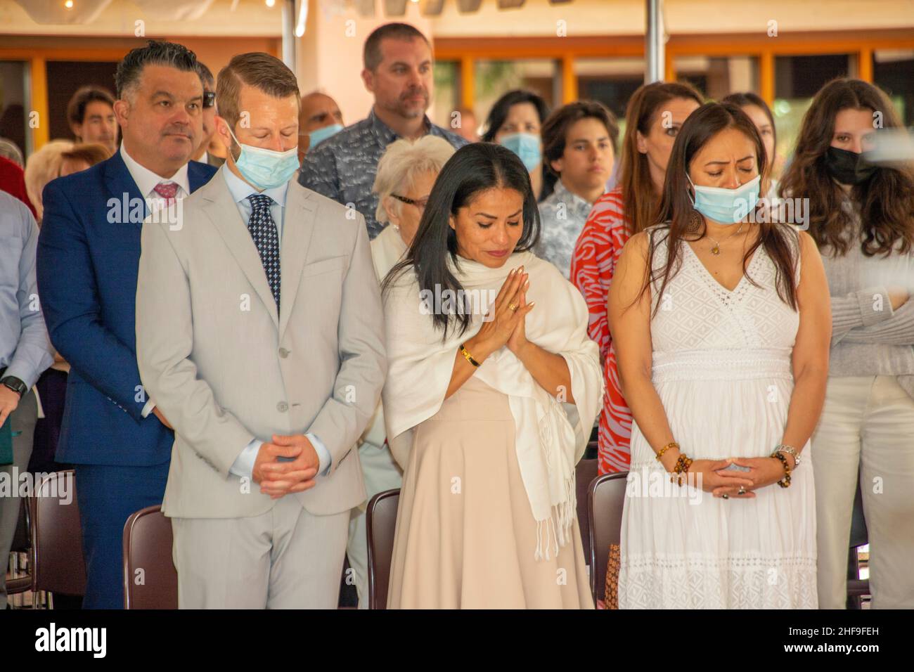 Masqués contre la pandémie du coronavirus, les candidats au baptême des adultes et leurs familles prient patiemment dans une église catholique de Californie. Banque D'Images