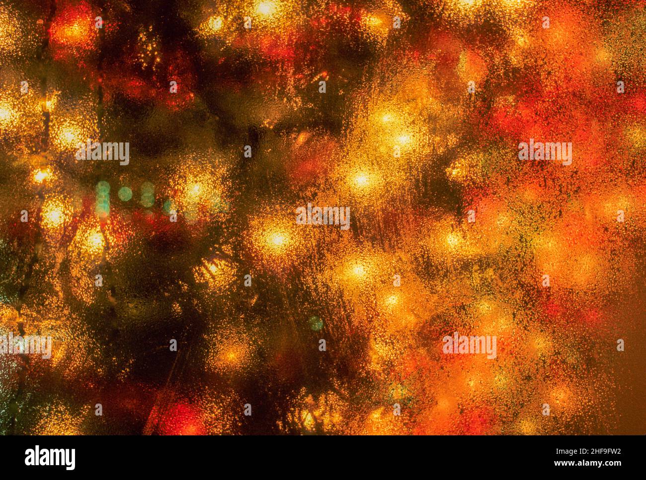 Les lumières d'un arbre de Noël coloré sont diffusées par condensation sur une fenêtre lors d'une nuit d'hiver à Cambridge, ma. Banque D'Images
