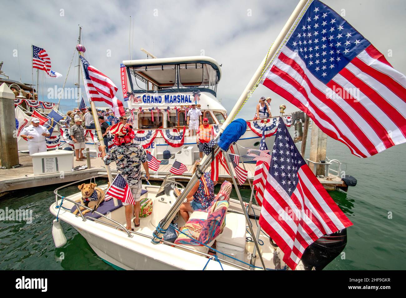 Un skiff passe devant le yacht du Grand Marshall pour un bref appel social avant de partir pour célébrer le 4 juillet à Newport Beach, CA. Banque D'Images