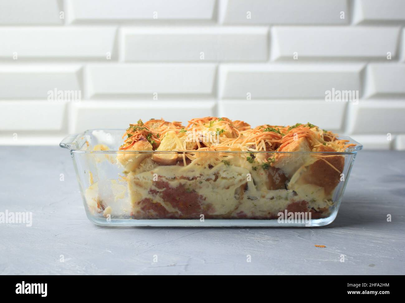 Sélection de pains maison Focus Pudding avec saucisse et fromage cheddar râpé, servi sur un plat de cuisson transparent Banque D'Images