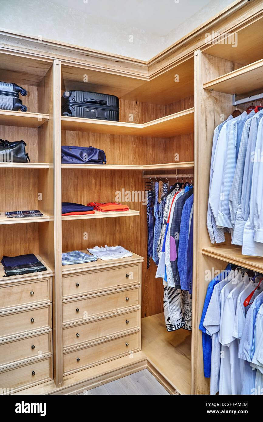 Penderie élégante avec meubles en érable massif et bois de placage pour ranger les vêtements avec moulures en couronne dans l'appartement Banque D'Images