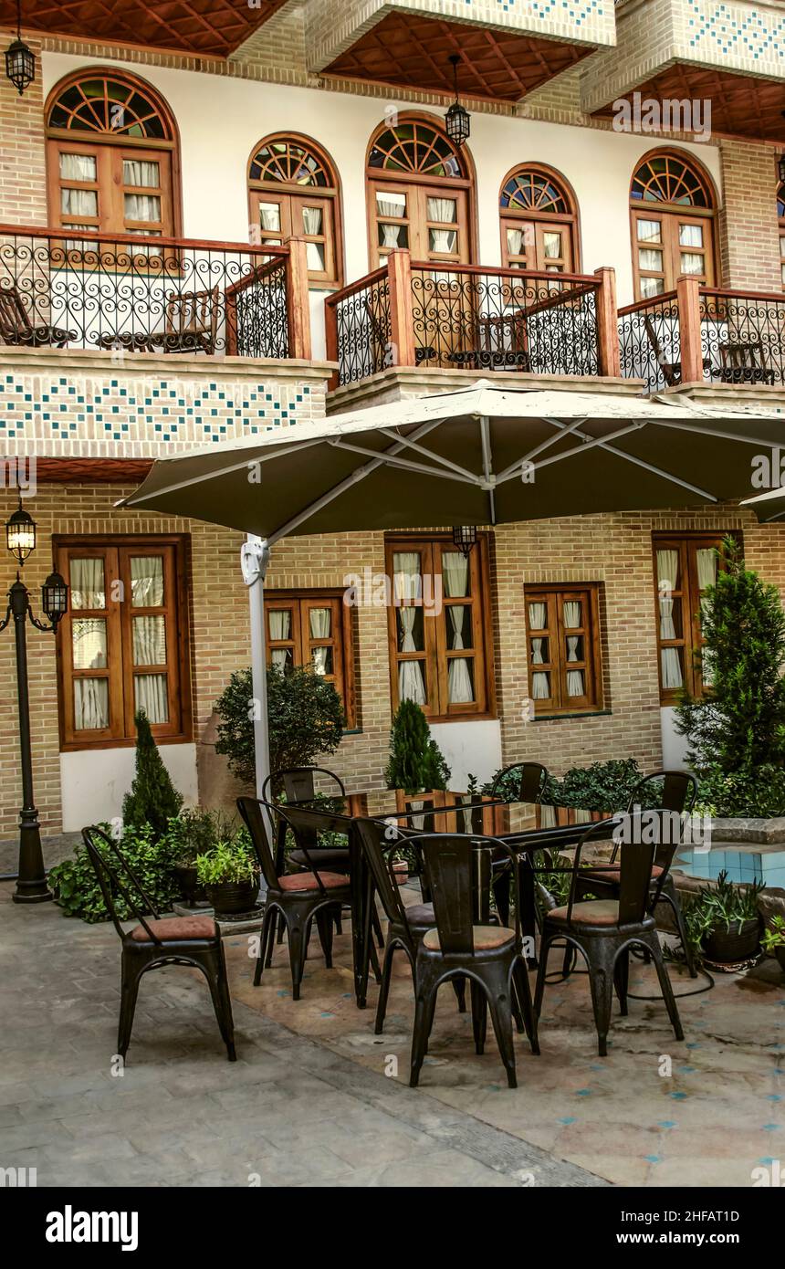 Table et chaises sous une verrière près de la piscine avec une fontaine parmi les fleurs dans le jardin de cour de l'hôtel "Arménie" dans le quartier arménien Banque D'Images