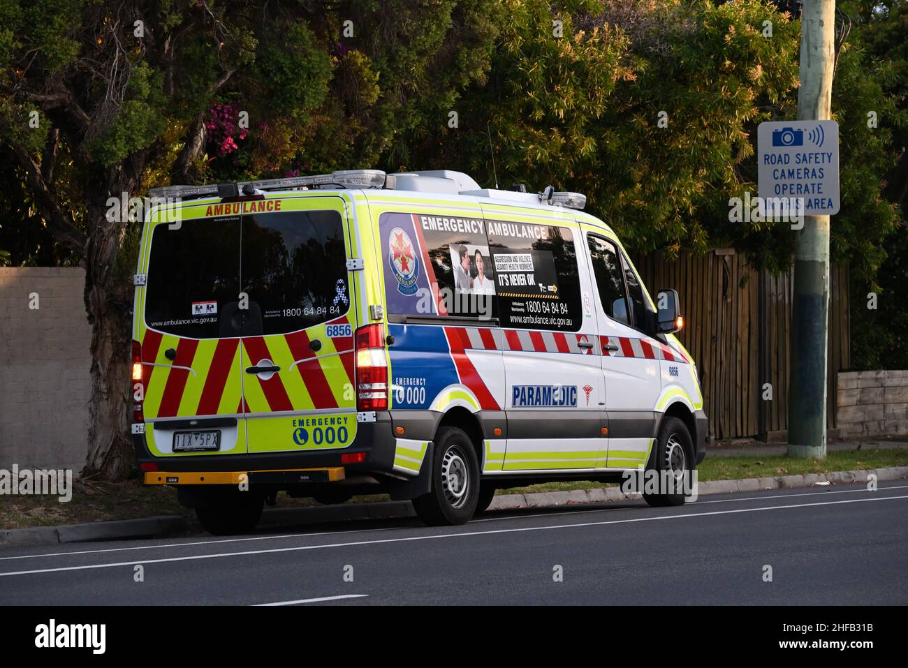 Ambulance véhicule paramédical Victoria stationné sur le côté de la route, feux de détresse allumés, avec message d'agression et de lutte contre la violence Banque D'Images