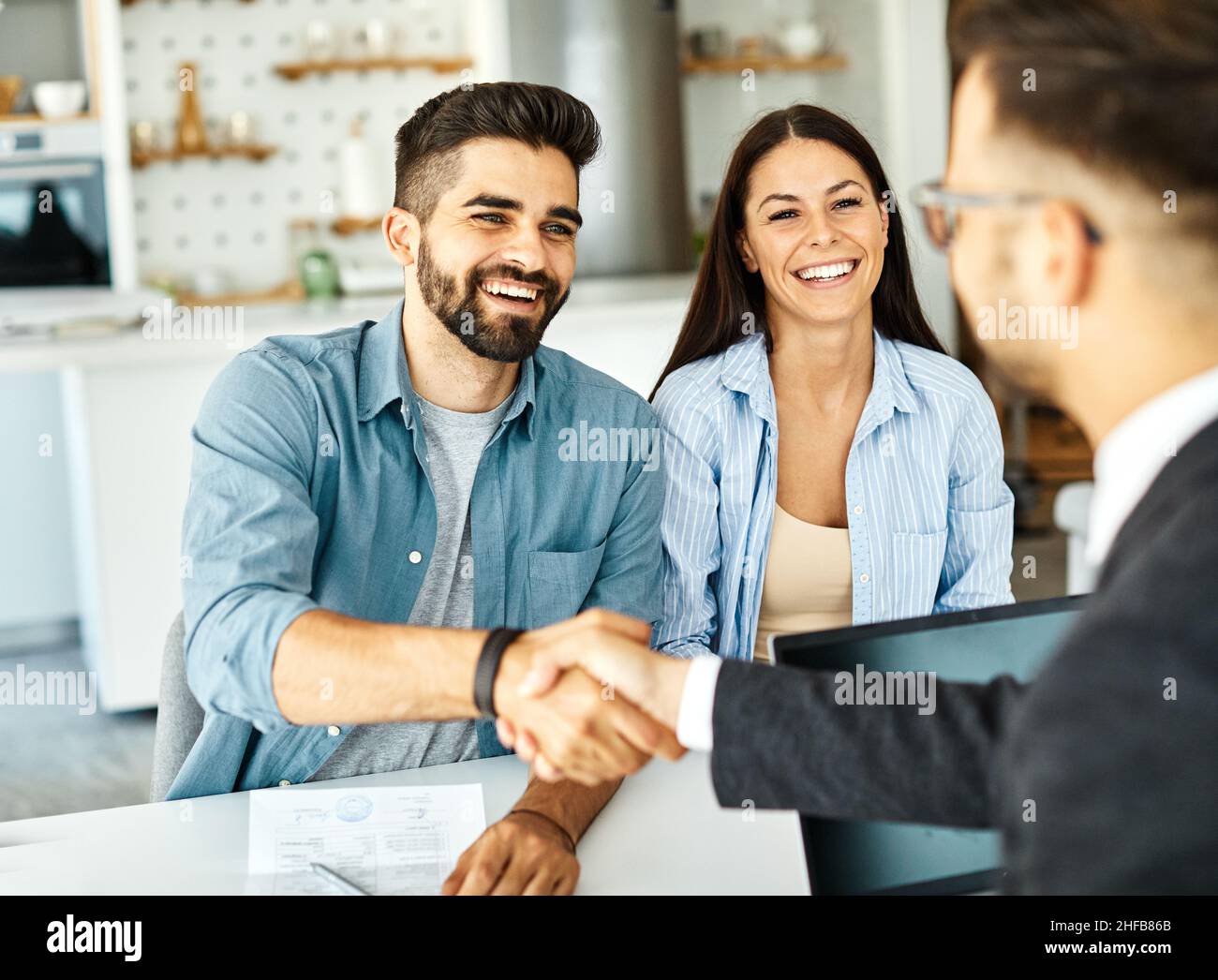un jeune couple qui tremble les mains traite contrat d'investissement immobilier agent d'accord d'affaires poignée de main signature Banque D'Images