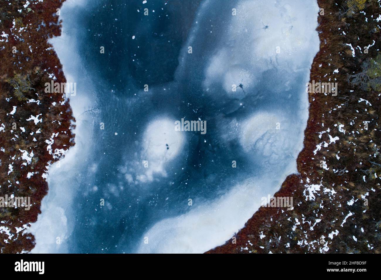 Une antenne d'un petit lac de tourbière recouvert d'une glace sombre avec quelques motifs en Estonie. Banque D'Images