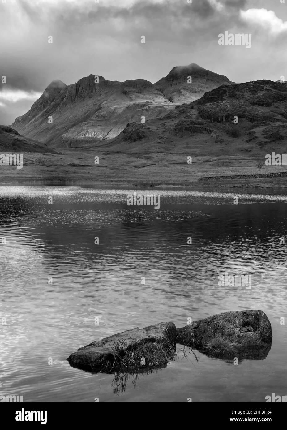 Noir et blanc paysage épique de lumière de lever de soleil sur Blea Tarn dans le Lake District avec une lumière étonnante sur les montagnes lointaines Banque D'Images