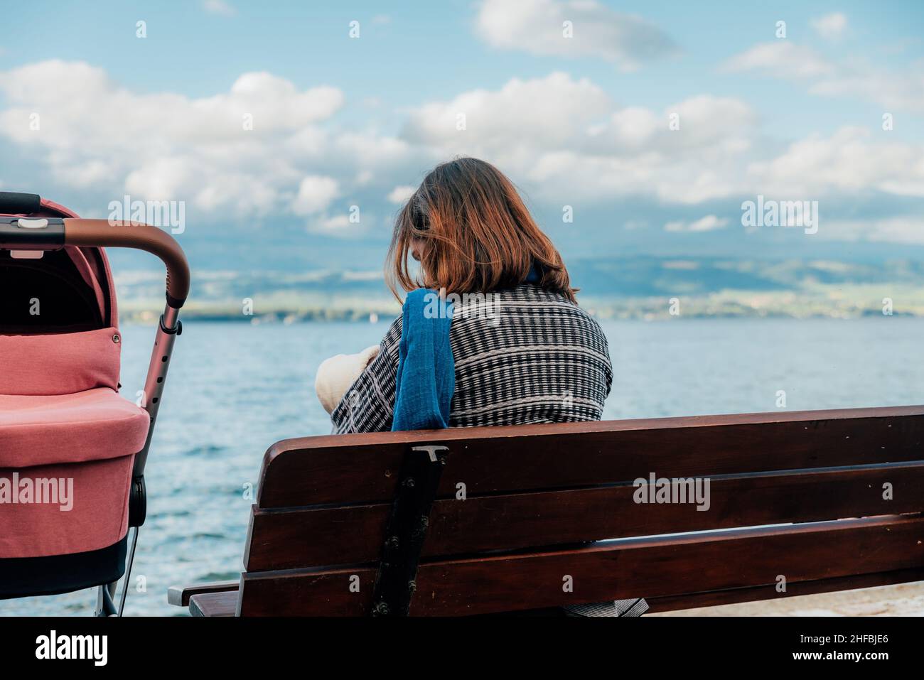 Mère avec bébé assis sur un banc au bord du lac Banque D'Images