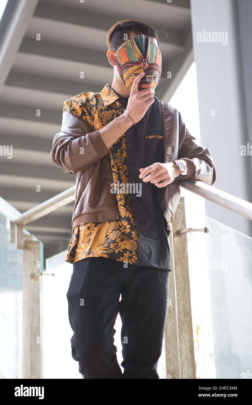 Un jeune modèle masculin habillé en indonésien Batik tient un masque javanais au long Museum, West Bund, Shanghai Chine Banque D'Images