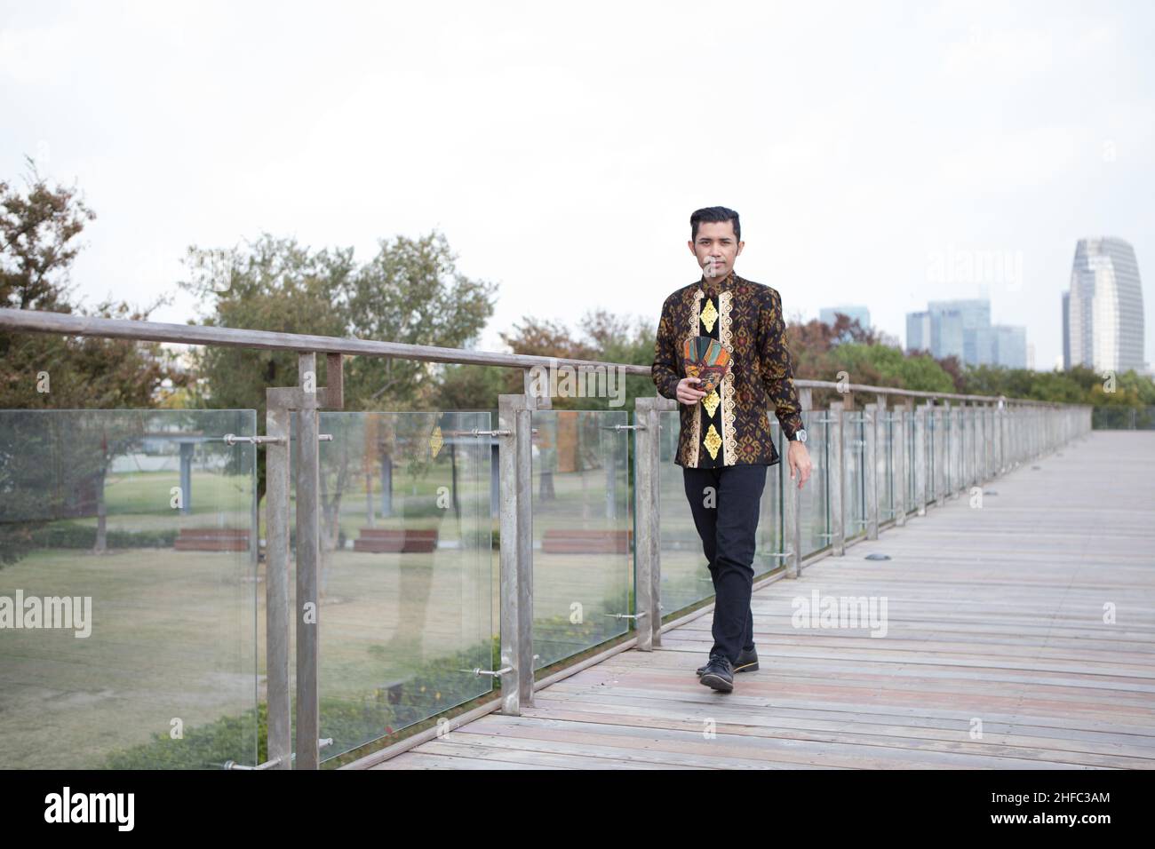 Un jeune modèle masculin vêtu de Batik indonésien avec un motif floral balinais marche au long Museum, West Bund, Shanghai en Chine Banque D'Images