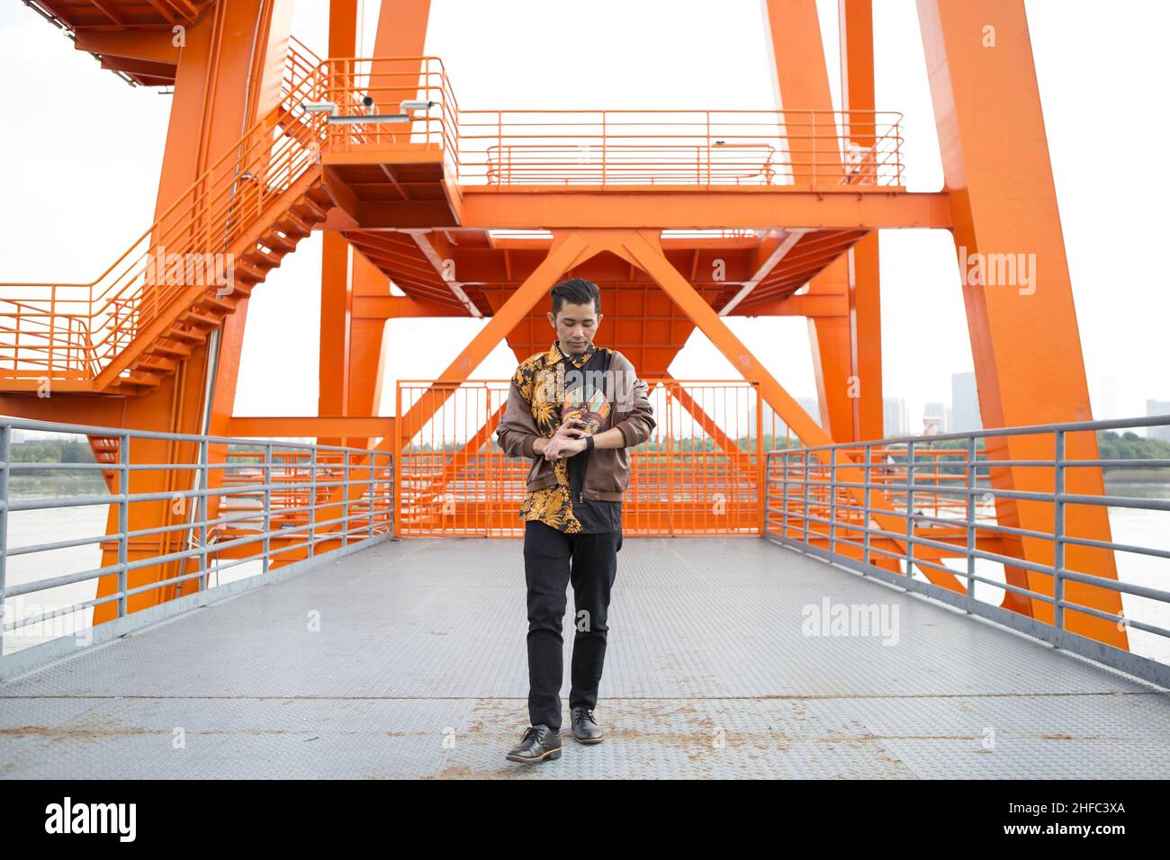 Un jeune homme vêtu de Batik indonésien tient un masque javanais et regarde une montre au long Museum, West Bund, Shanghai Chine Banque D'Images