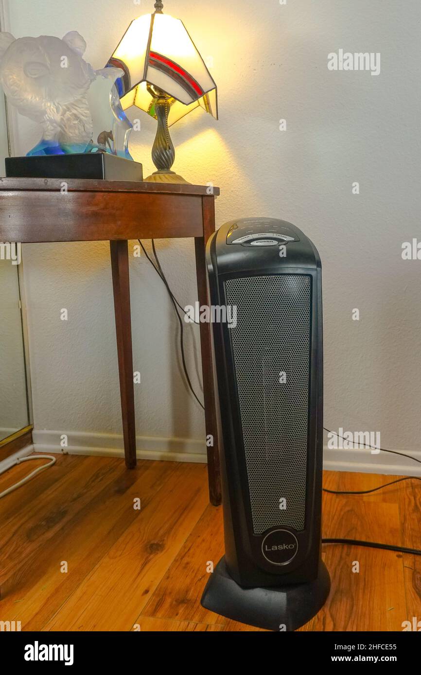 Chauffage électrique de pièce ou d'espace sur un plancher en bois stratifié à côté d'une petite table avec une lampe de table dans un salon de Californie . Banque D'Images