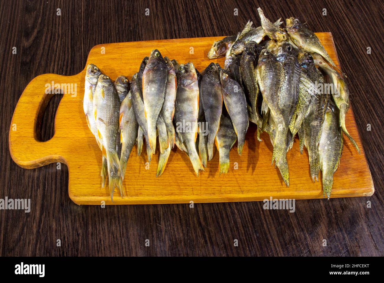 Le poisson salé séché repose sur le plateau. Fond marron. Banque D'Images