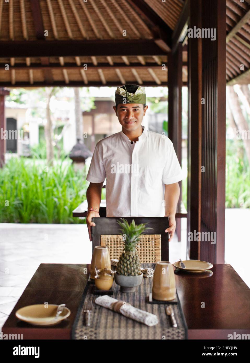 Un jeune serveur balinais fixe une table pour le déjeuner au restaurant Gong, Kayumanis Gangsa, Bali, Indonésie. Banque D'Images