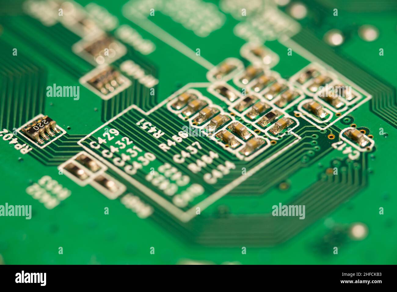 De nombreux petits composants électroniques sont soudés sur une carte de circuit imprimé (PCB) verte. Banque D'Images