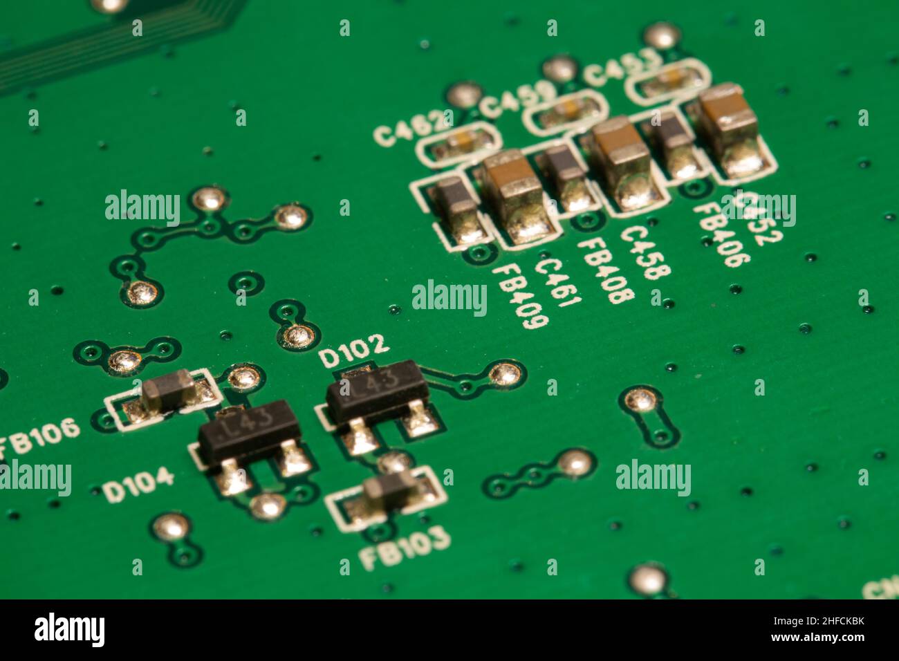 De nombreux petits composants électroniques sont soudés sur une carte de circuit imprimé (PCB) verte. Banque D'Images