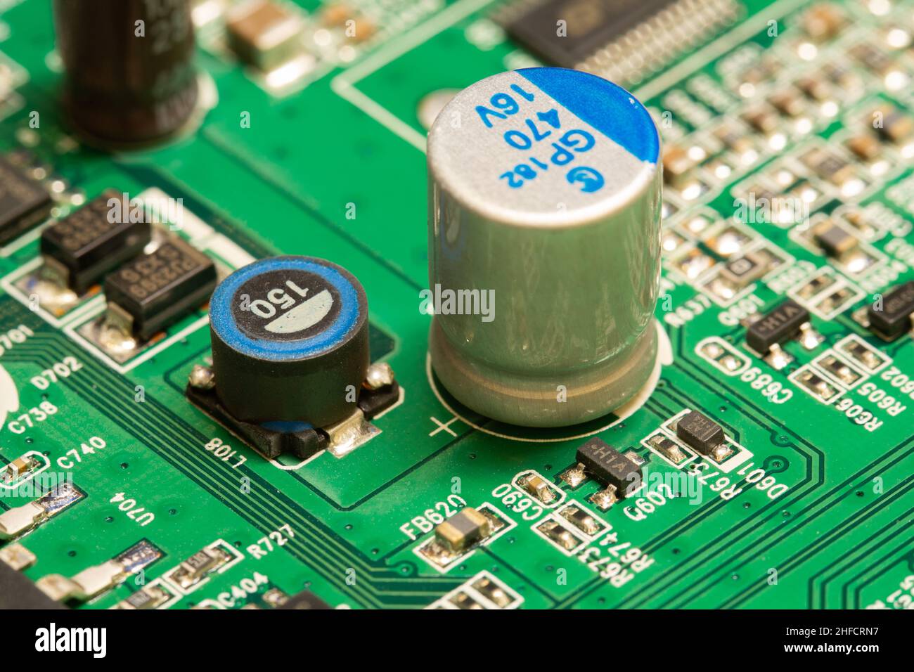 Condensateur électrolytique soudé sur une carte de circuit imprimé (PCB) verte. Banque D'Images