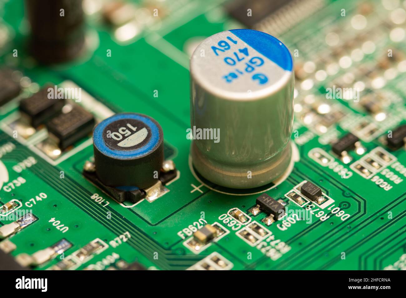 Condensateur électrolytique soudé sur une carte de circuit imprimé (PCB) verte. Banque D'Images