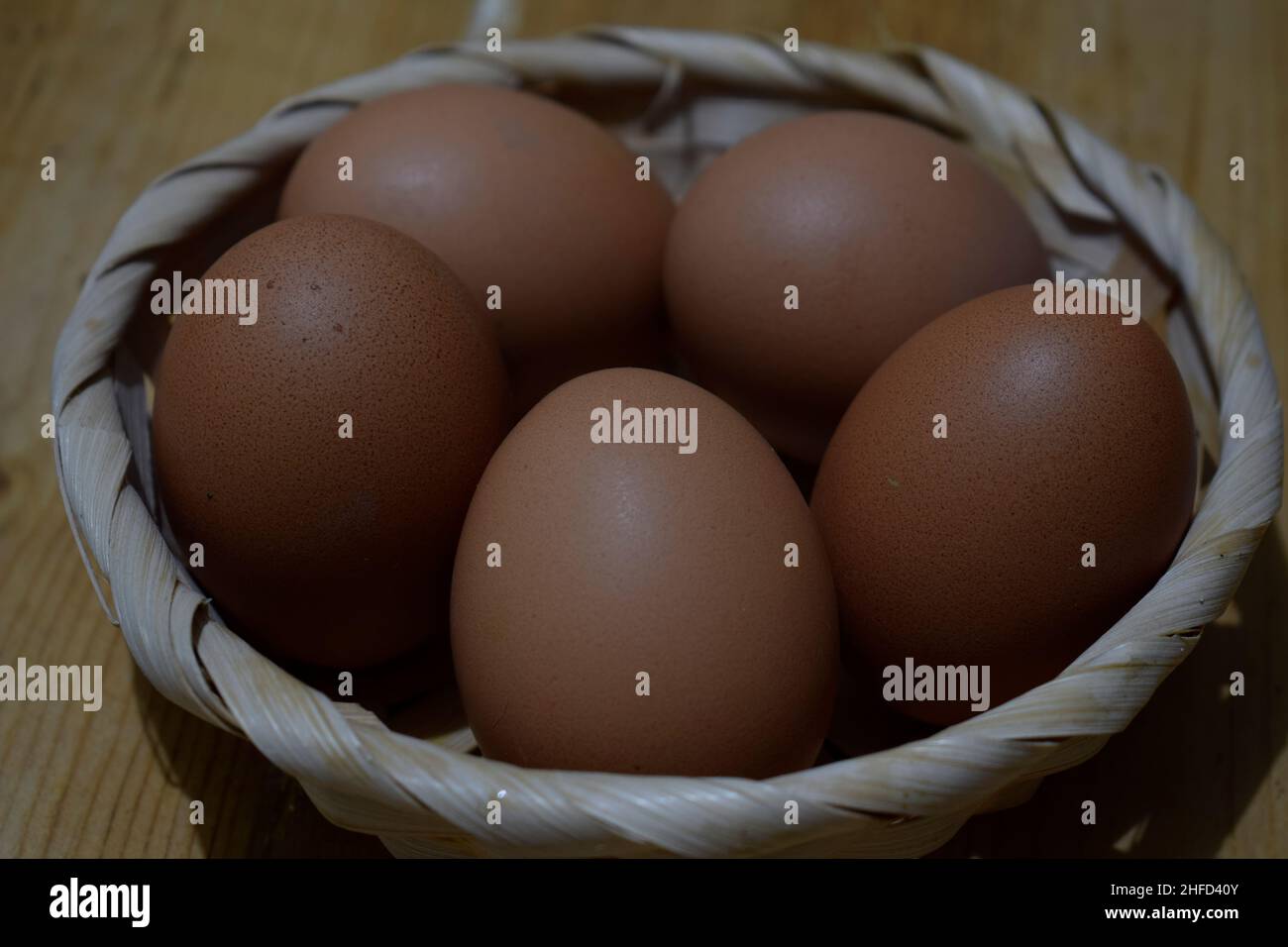 Faites dorer les œufs de poulet dans un panier de feuilles de palmier sur une table rustique en bois Banque D'Images