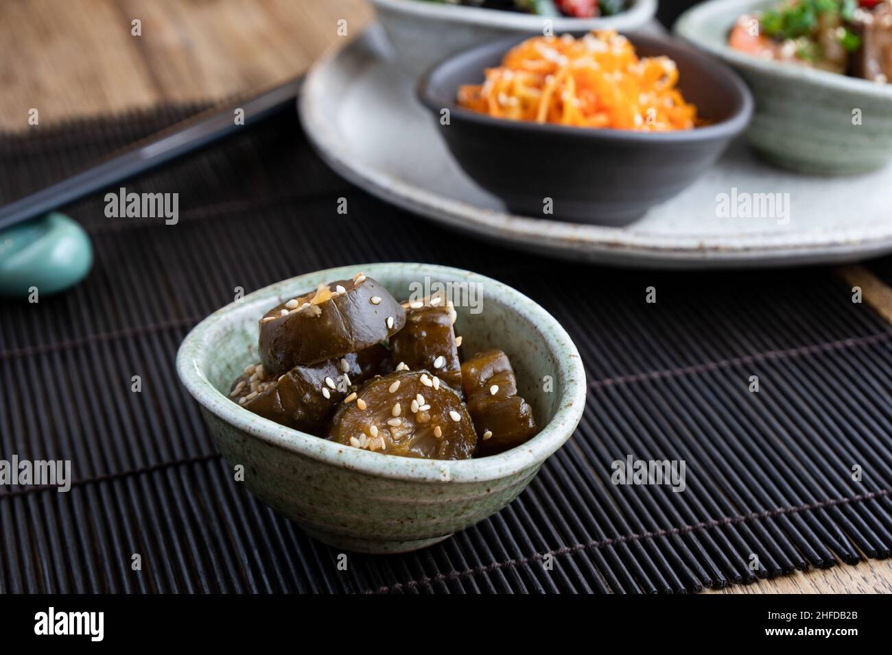 Salade japonaise de concombre marinée aux graines de sésame.Tapis en bambou et baguettes en arrière-plan. Banque D'Images