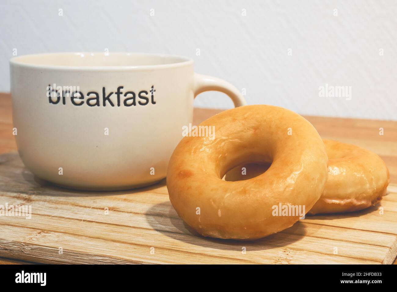 Deux beignets sucrés classiques et une tasse de t-shirt ou de café sur un support en bois.Image du concept de petit déjeuner. Banque D'Images