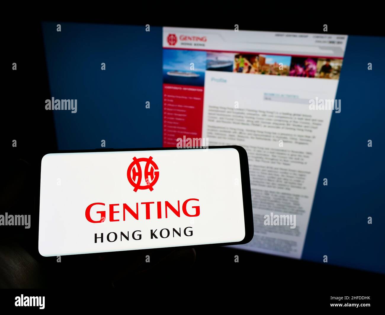 Personne tenant un smartphone avec le logo de la société de tourisme Genting Hong Kong Limited à l'écran devant le site Web.Mise au point sur l'affichage du téléphone. Banque D'Images