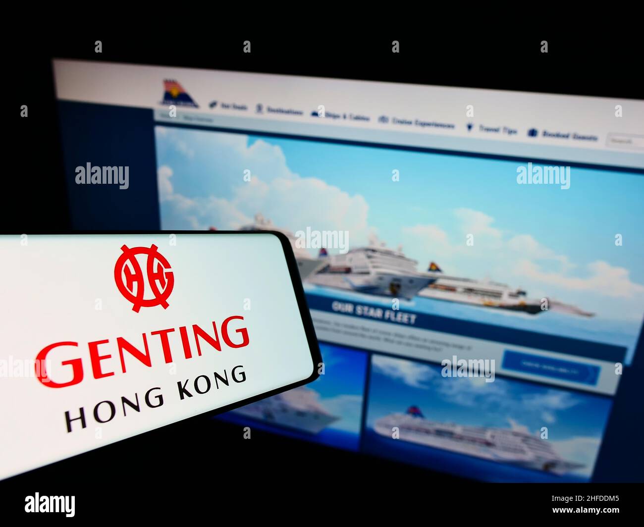 Smartphone avec le logo de la société de tourisme Genting Hong Kong à l'écran devant le site Web de Star Cruises.Effectuez la mise au point au centre-droit de l'écran du téléphone. Banque D'Images