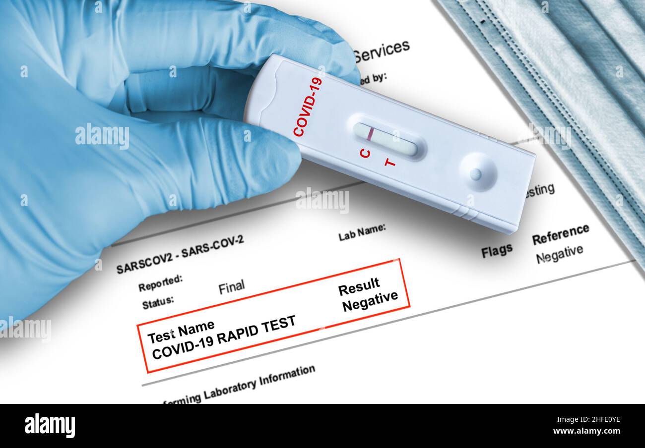 Résultat du test d'antigène négatif COVID-19 en utilisant un dispositif d'auto-test rapide tenu à la main dans un gant médical avec un masque facial médical en arrière-plan. Banque D'Images