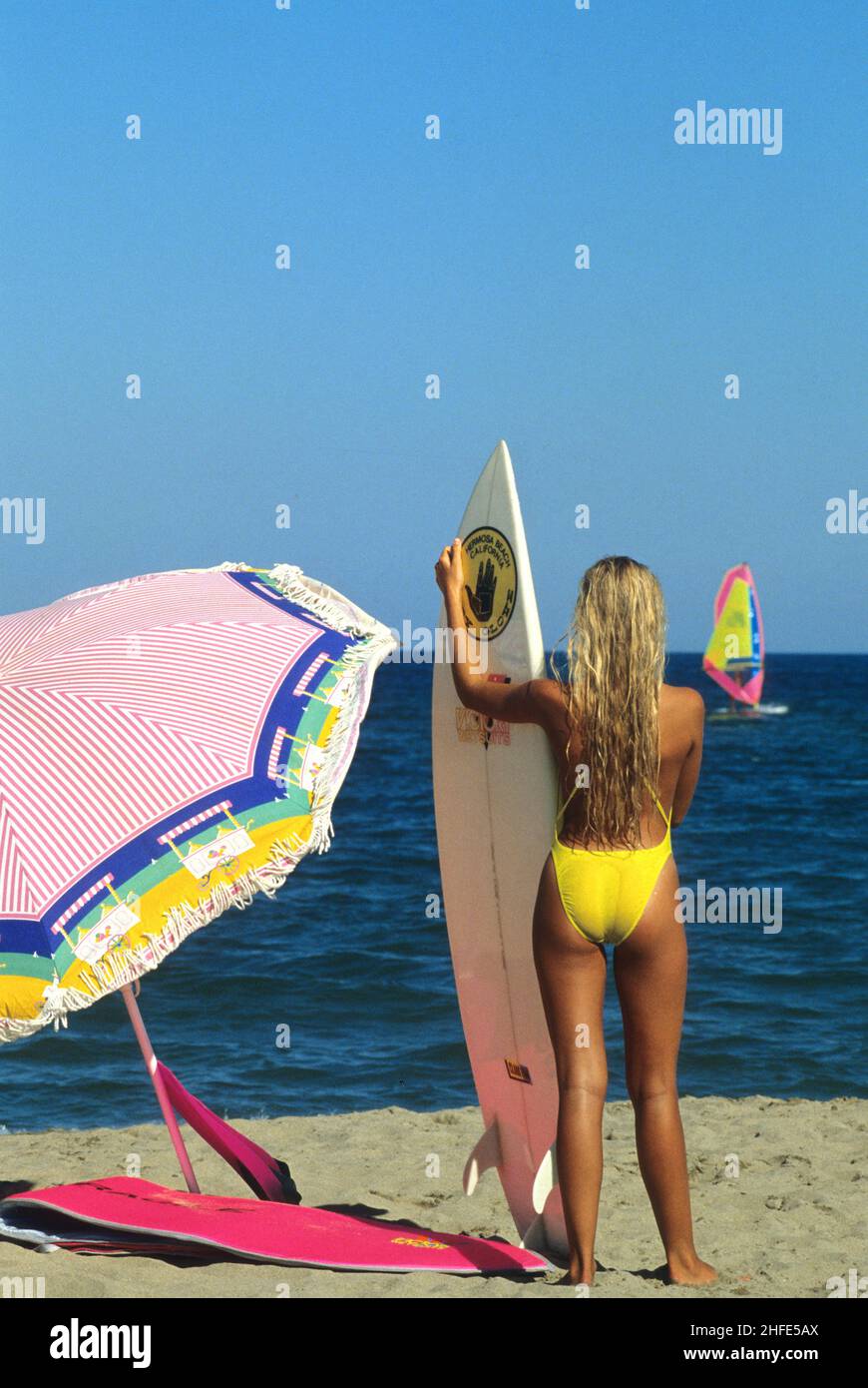 vue arrière beauté cheveux blond attrayant silhouet sportif avec surf stand sur la plage bleu mer fond Banque D'Images