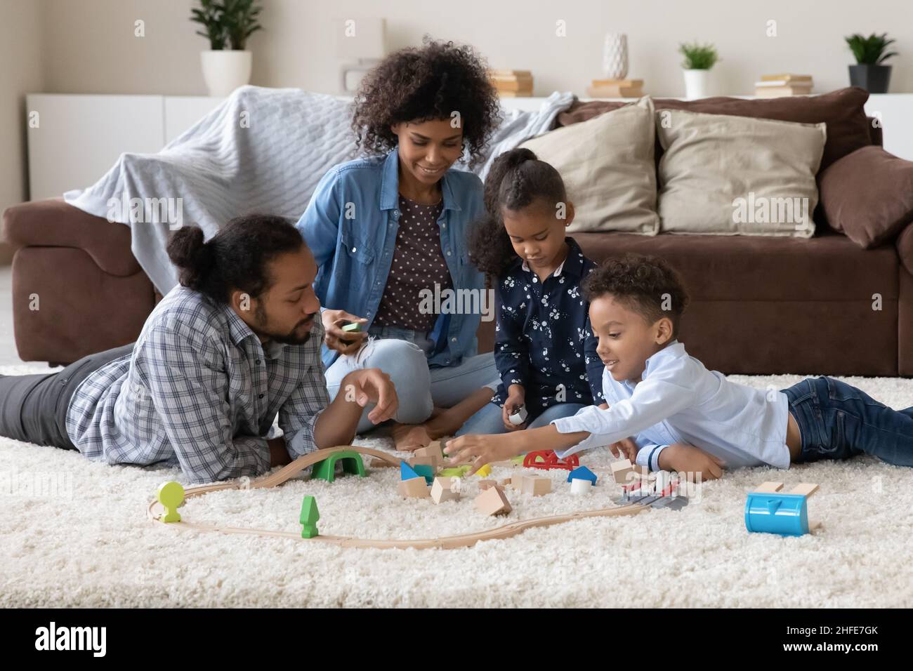 Des parents heureux aidant deux enfants à construire un modèle de route de jouet Banque D'Images