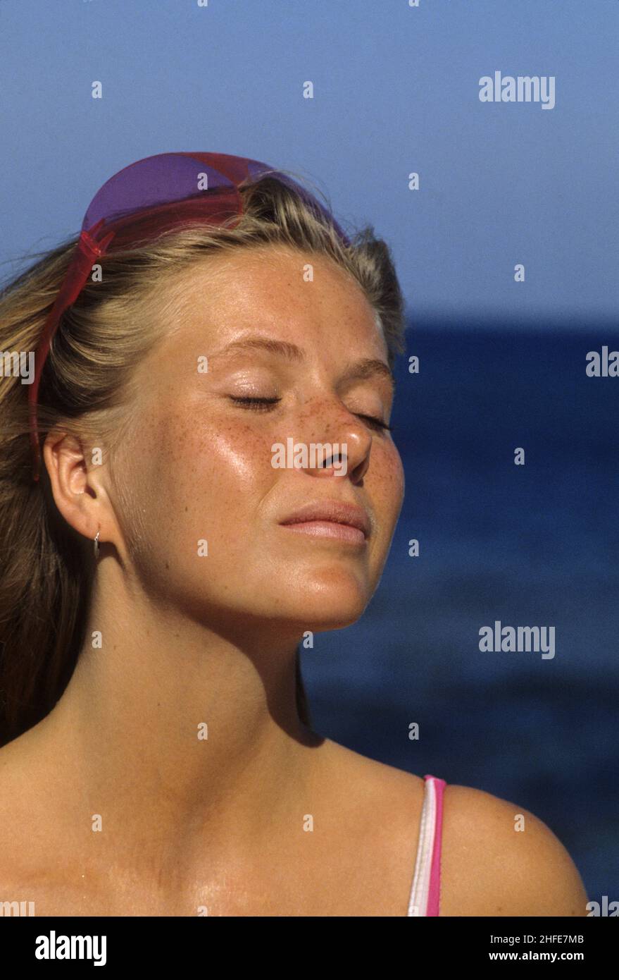 cheveux blond vue avant portrait naturel yeux fermés profil vue caméra bleu ciel eau de mer arrière-plan sensation de brise Banque D'Images