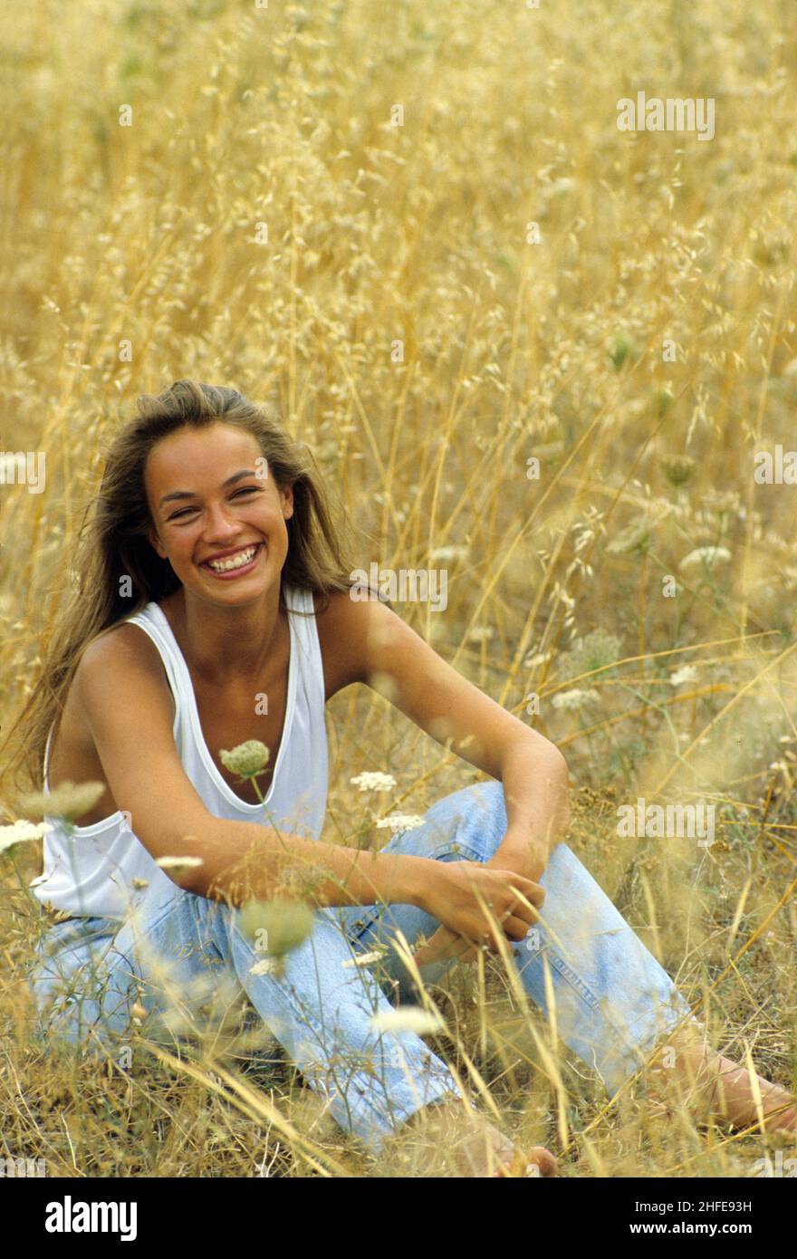 auburn cheveux bleus yeux jeunes femmes assis sur le pays des herbes jaunes sourire bonne vue caméra avant Banque D'Images