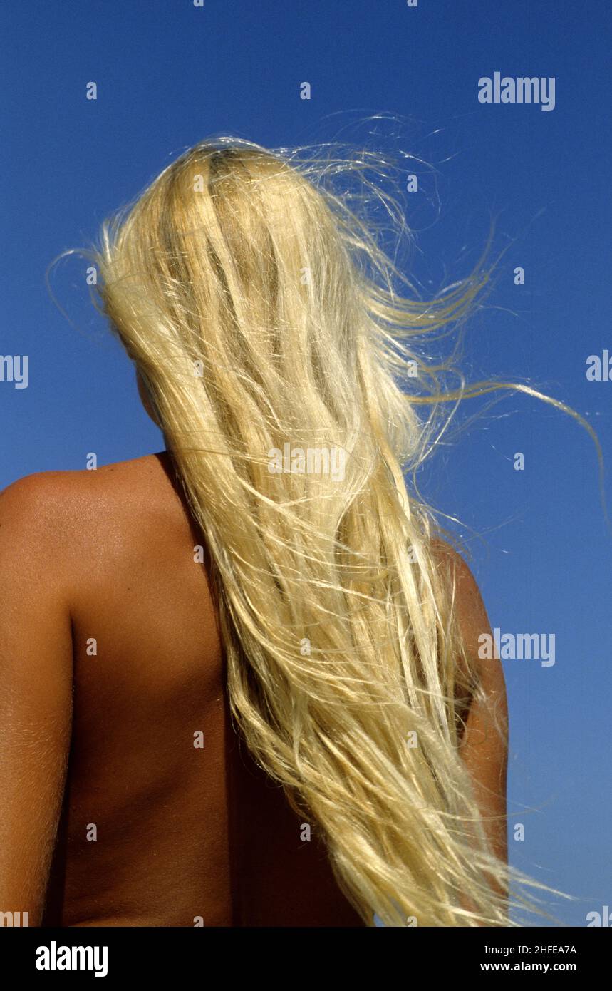 très long cheveux blond jeune femme beauté sourire profil avant bleu ciel fond Banque D'Images