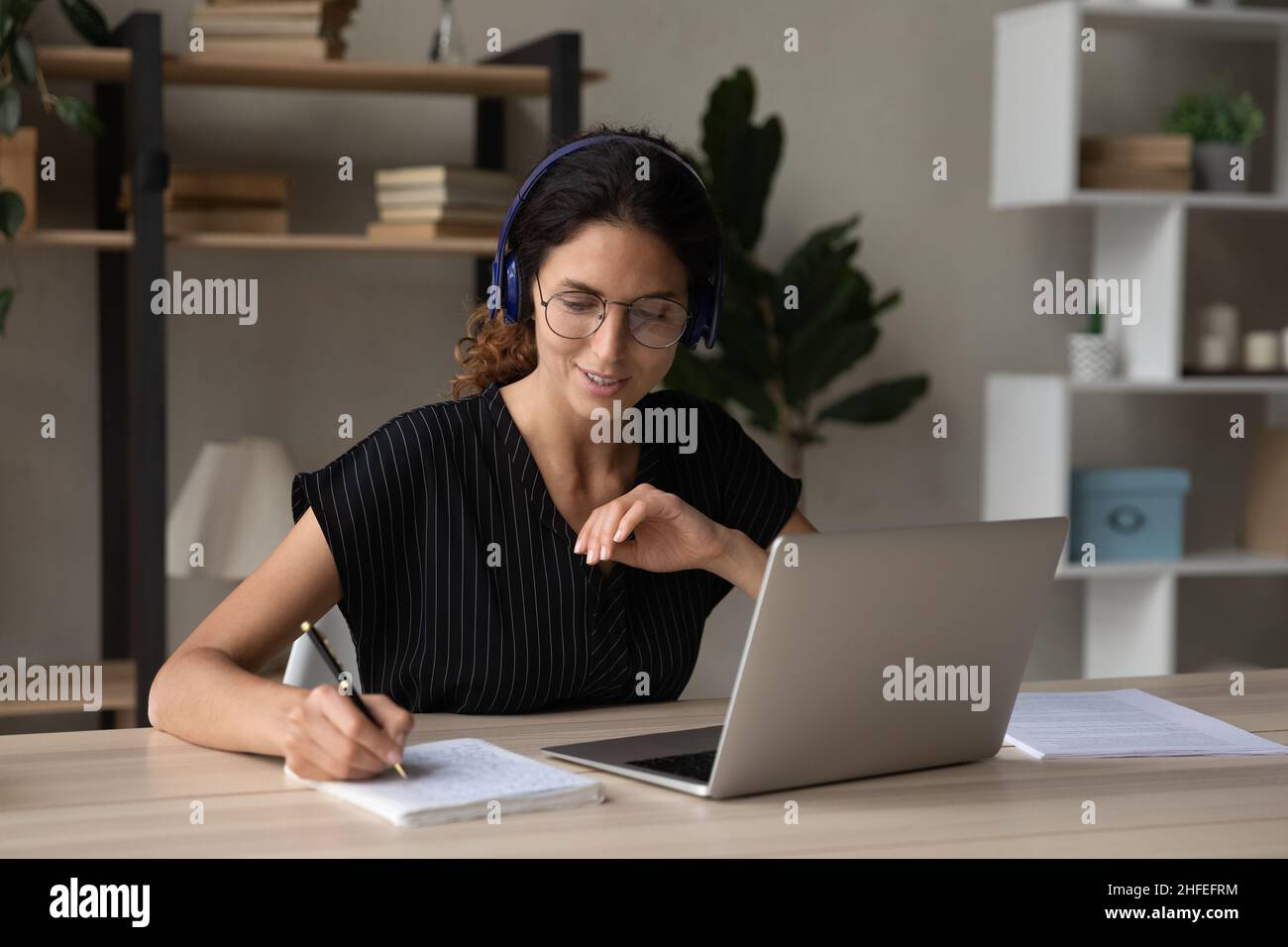 Heureuse femme millénaire intéressée étudiant sur les cours en ligne. Banque D'Images