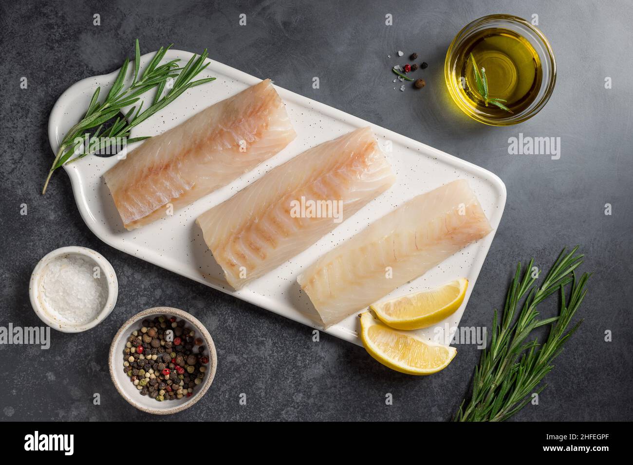 Filet de morue cru avec ingrédients pour la cuisson à table sombre Banque D'Images
