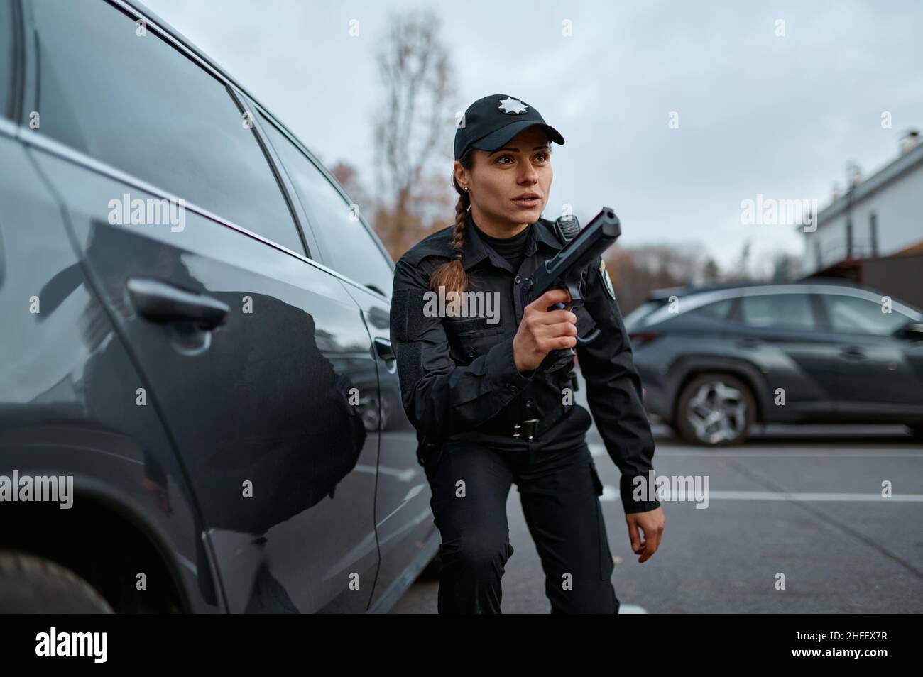 Femme de police qui cherche un fusil à proximité d'une voiture Banque D'Images