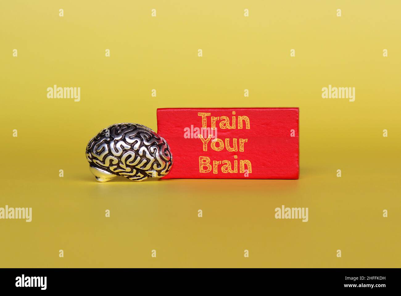 Modèle de cerveau et cube en bois rouge avec texte train Your Brain sur fond jaune Banque D'Images