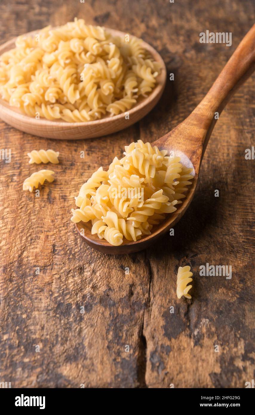 variété de pâtes non cuites dans une cuillère en bois, sur fond en bois, régime alimentaire et concept alimentaire, prises dans une faible profondeur de champ avec espace de copie Banque D'Images