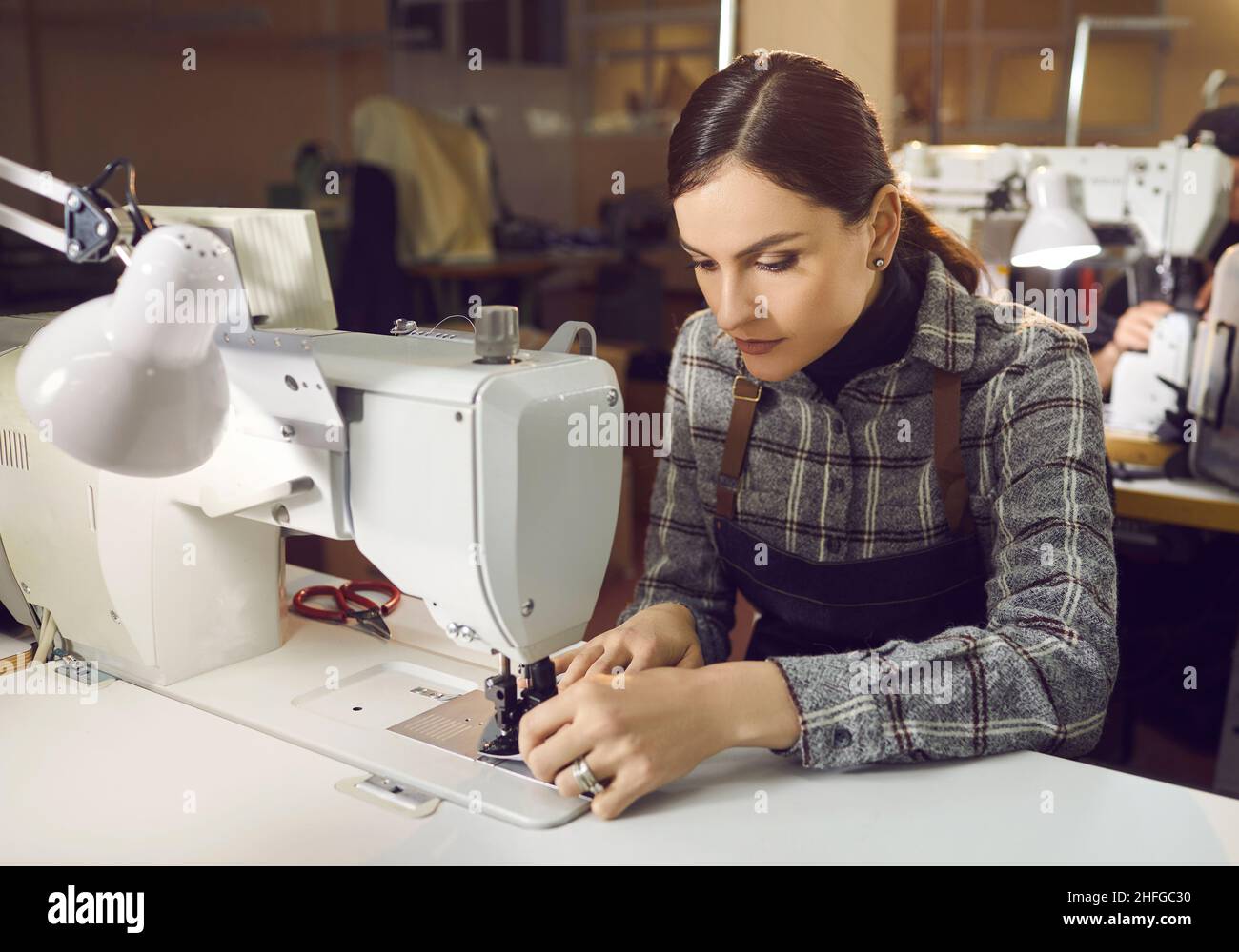 Jeune femme caucasienne travaillant à coudre sur machine sur le lieu de travail Banque D'Images