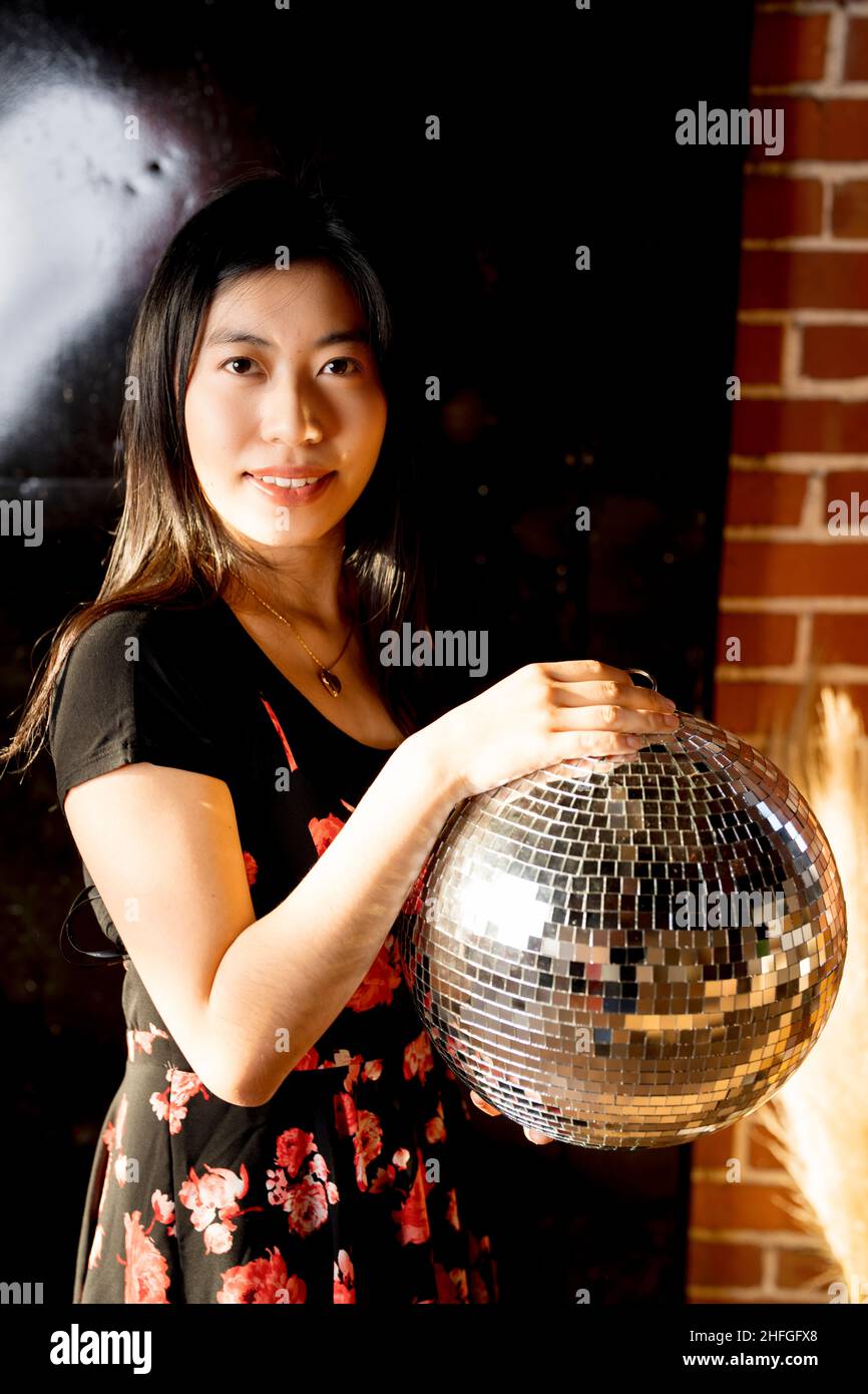 Jeune femme d'Asie de l'est en robe à imprimé fleuri tenant un ballon de miroir Banque D'Images