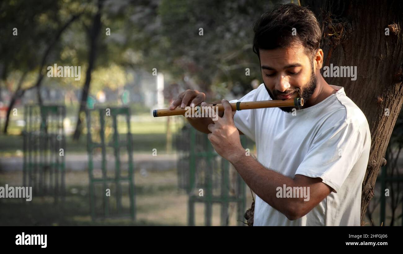Joueur de Bansuri jouant de la musique au soleil à Park - Indian Flûte Player Banque D'Images
