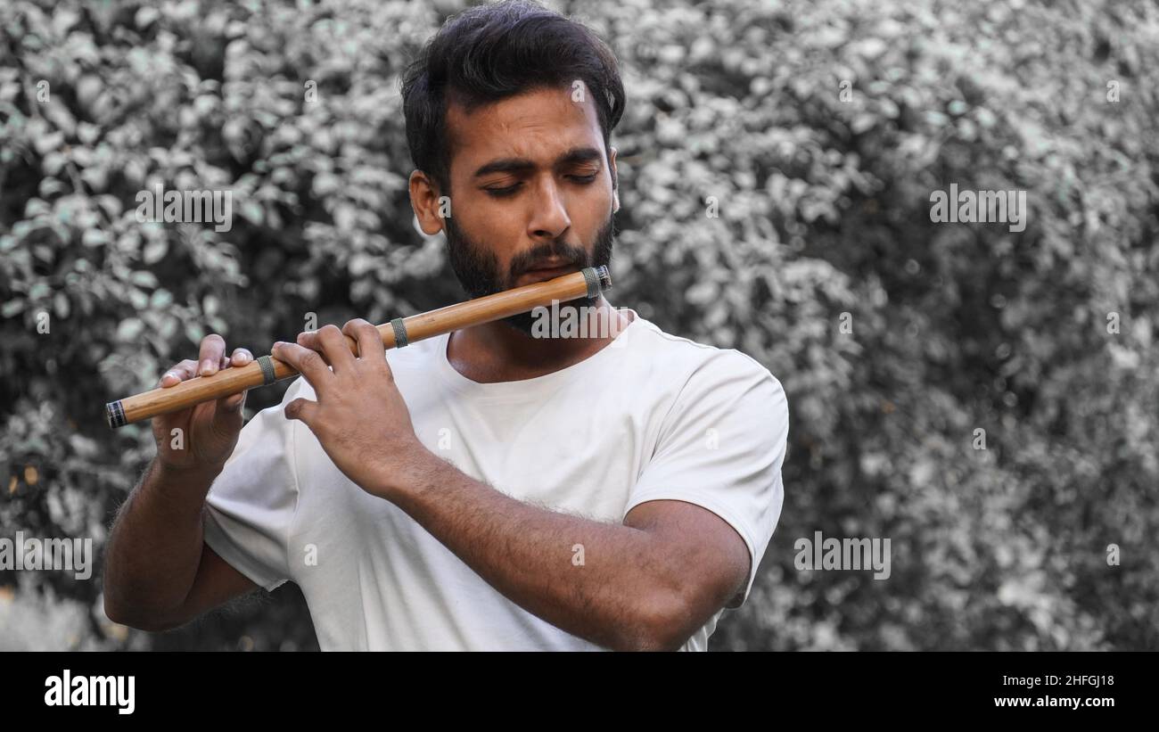 Joueur de Bansuri jouant de la musique au soleil à Park - Indian Flûte Player Banque D'Images