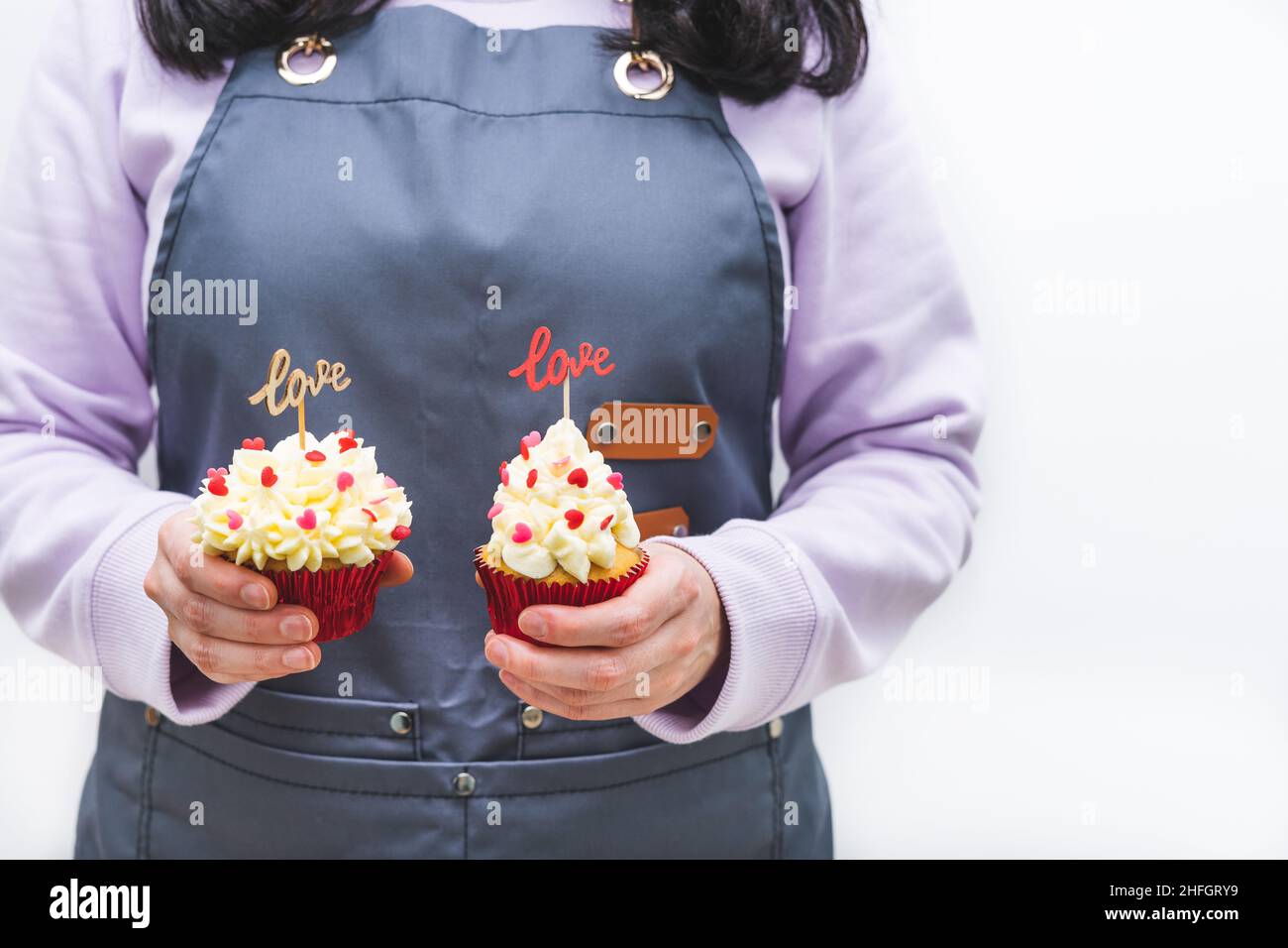 Serveuse avec deux cupcakes décorés avec des coeurs rouges et une enseigne en bois avec des lettres D'AMOUR.Concept de la Saint-Valentin et de la fête des mères.Blanc Banque D'Images