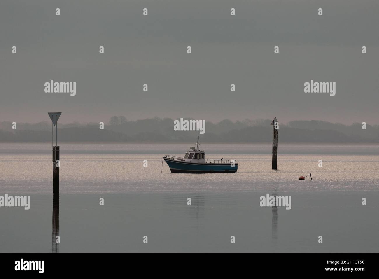Petit bateau de pêche par une journée calme dans le port de Langstone près de Havant.Brume matinale qui embrasse la côte de l'île Hayling. Banque D'Images