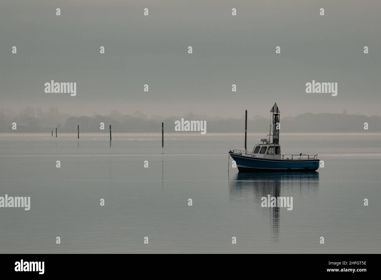 Petit bateau de pêche par une journée calme dans le port de Langstone près de Havant.Brume matinale qui embrasse la côte de l'île Hayling. Banque D'Images