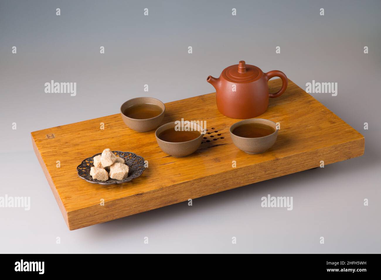 Une théière et trois tasses de thé pu-erh fraîchement préparé, sucre pressé.Un set sur une table en bois pour les cérémonies du thé. Banque D'Images