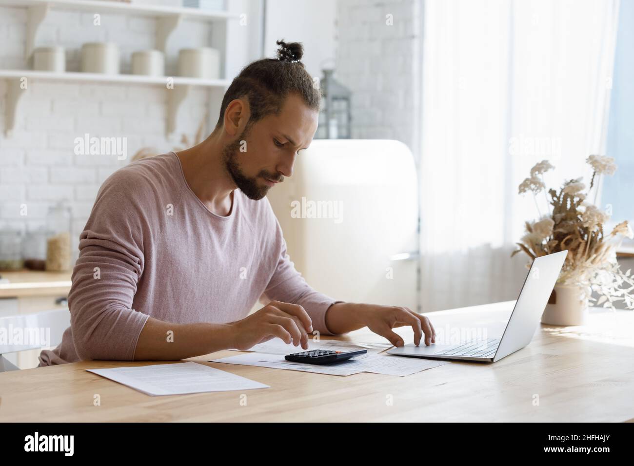 Un jeune homme concentré qui gère seul le budget du ménage à la maison. Banque D'Images