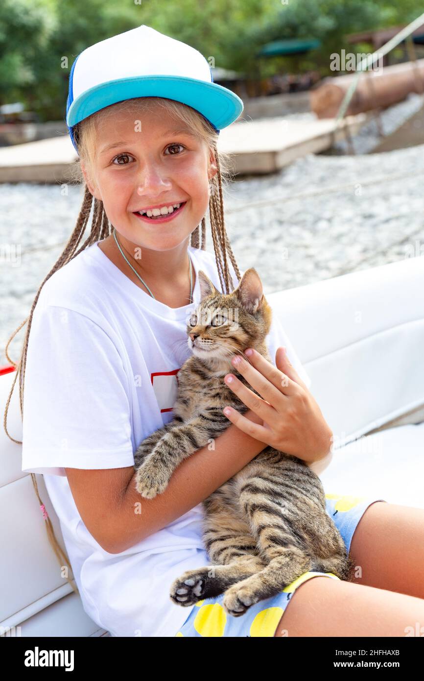 Jeune fille blanche en casquette de baseball avec visage amical tient  doucement tabby chaton, regardant l'appareil photo, souriant, assis dans le  bateau.Petits pourreurs de chat mignons Photo Stock - Alamy