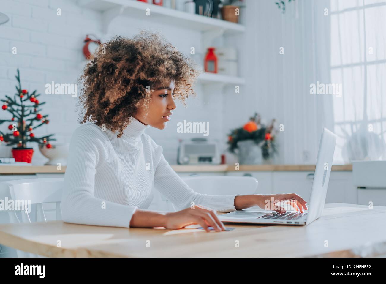 Lady avec la peau parfaite sombre tenant la carte de crédit et l'insertion des informations bancaires pour les achats en ligne se trouve près de l'ordinateur portable de près Banque D'Images